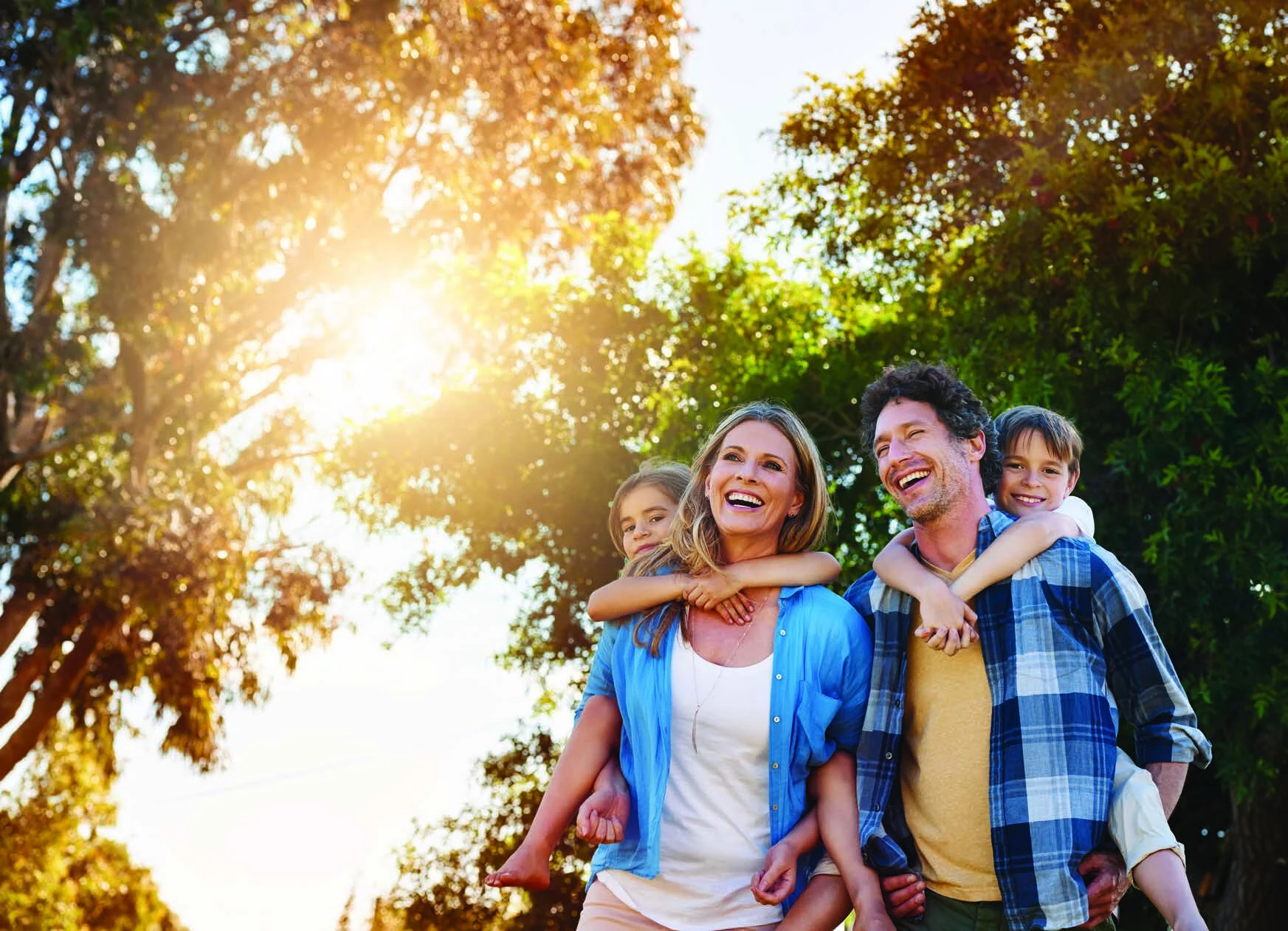 A laughing family of four outdoors in the sunshine