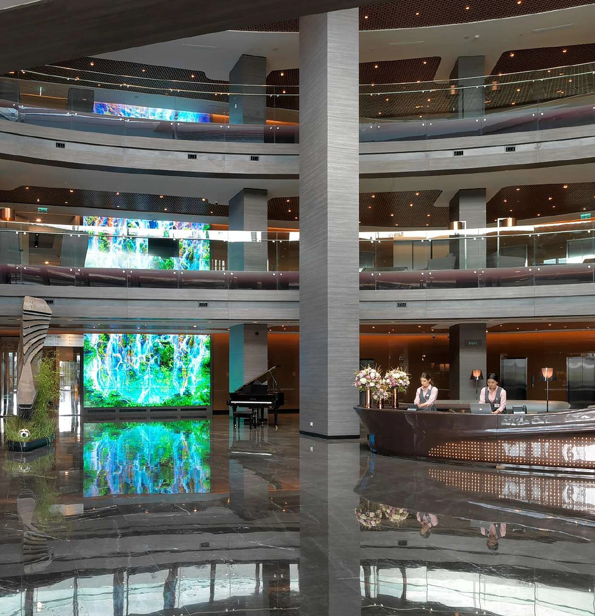 The atrium of Memorial Bahçelievler with a reception desk, a grand piano and a digital art wall